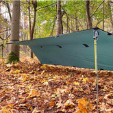 DD Superlight Tarp Small set up in forest, providing shelter over fallen leaves and showcasing its lightweight design.